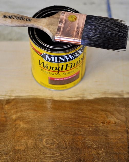 a paint can and brush sitting on top of a wooden table next to a piece of wood