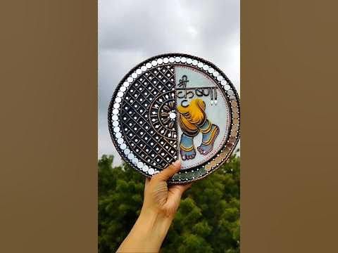 a person holding up a decorative plate in front of trees