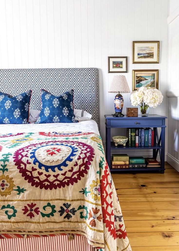 a bed sitting in a bedroom next to a night stand with flowers on top of it