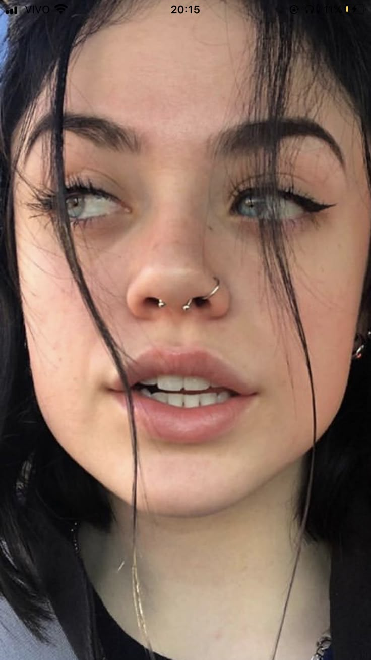 a close up of a person with piercings on her nose