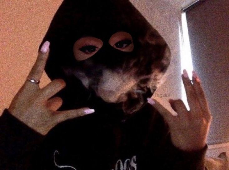 a woman in a black hoodie with her hands on her face and wearing a mask