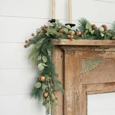 an old fireplace decorated with greenery and pine cones