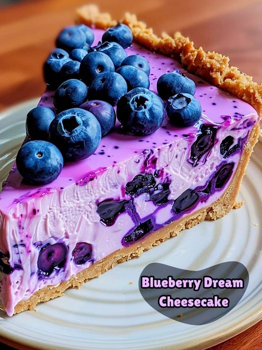 a slice of blueberry dream cheesecake on a plate with graham cracker crust