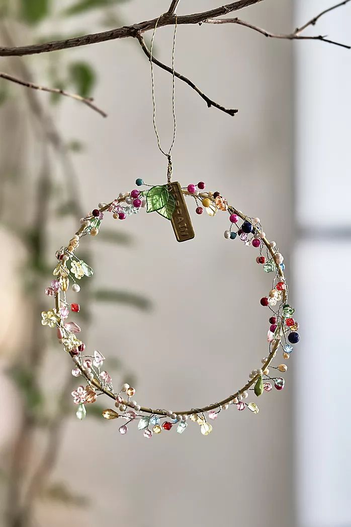 an ornament hanging from a tree branch with beads and charms on the end