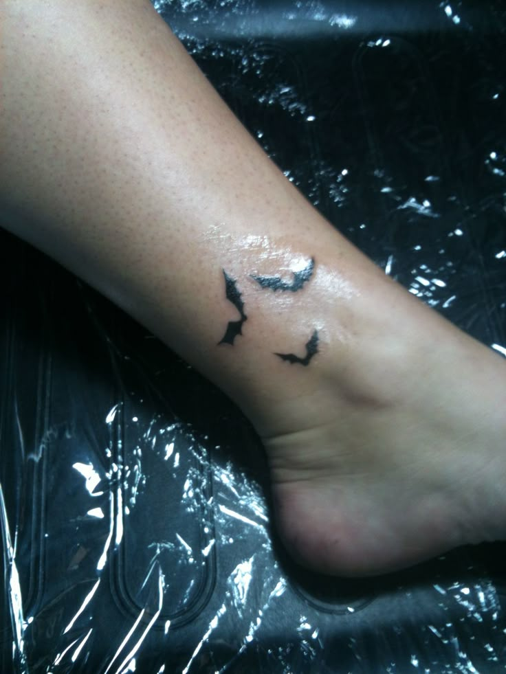 a person's foot with a small bird tattoo on the left side of their leg