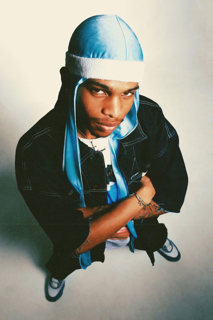 a young man wearing a blue hat and scarf with his arms crossed in front of him