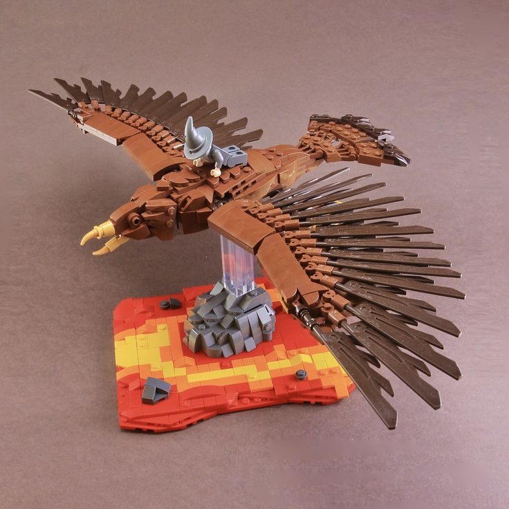 a lego eagle sitting on top of an orange and yellow piece of paper with spikes sticking out of it's wings