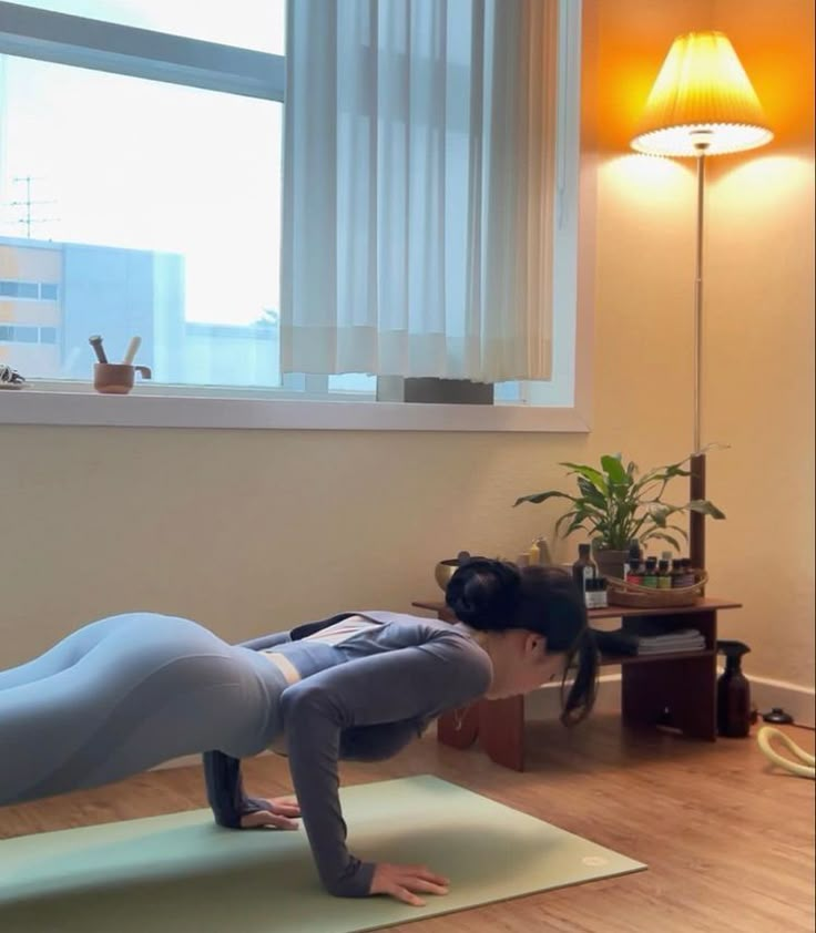 a woman is doing yoga in front of a window