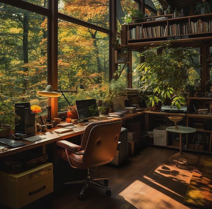 a home office with large windows and lots of books on the shelves, along with a desk