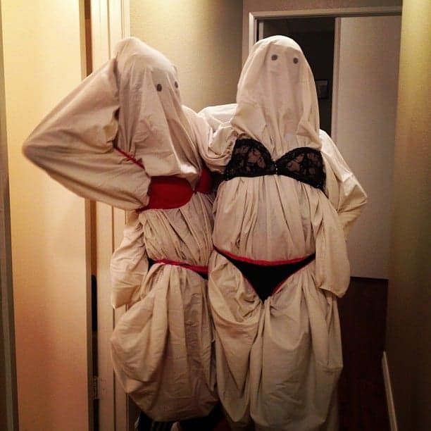 two women dressed in ghost costumes standing next to each other with their hands on their hips