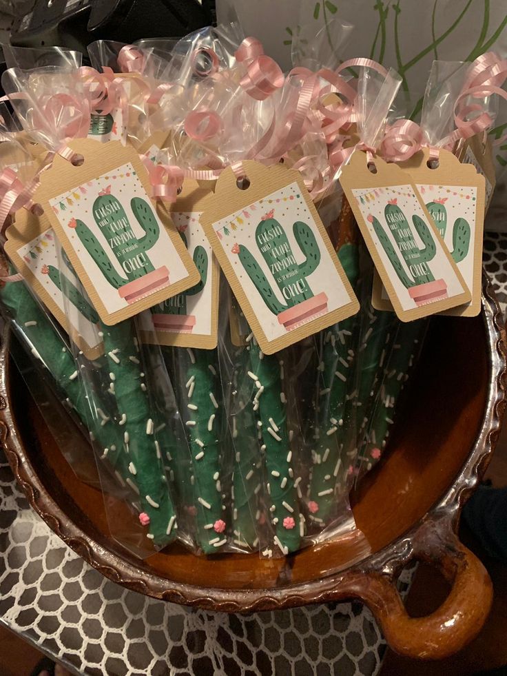 small cactus plant wrapped in cellophane and tied with pink ribbon on top of a wooden bowl