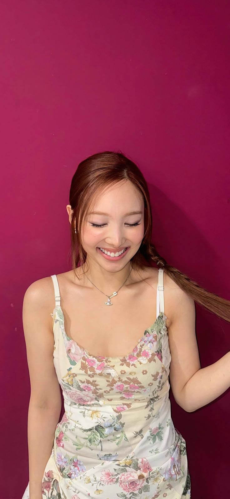 a woman with long hair standing in front of a pink wall