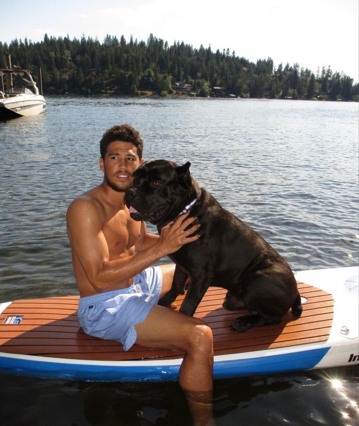 a man is sitting on a paddle board with his dog