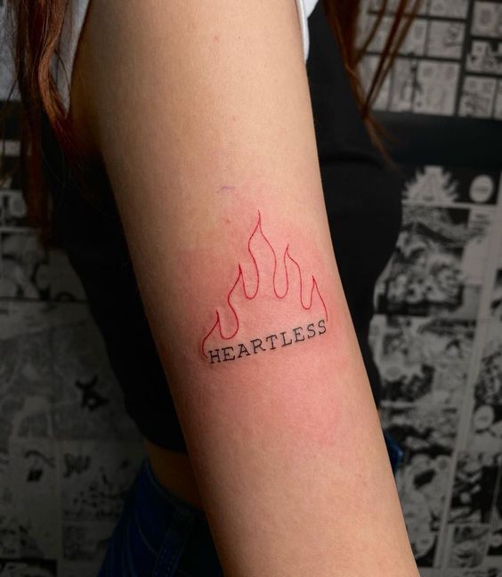 a woman's arm with the word heartless tattooed on it, in red ink