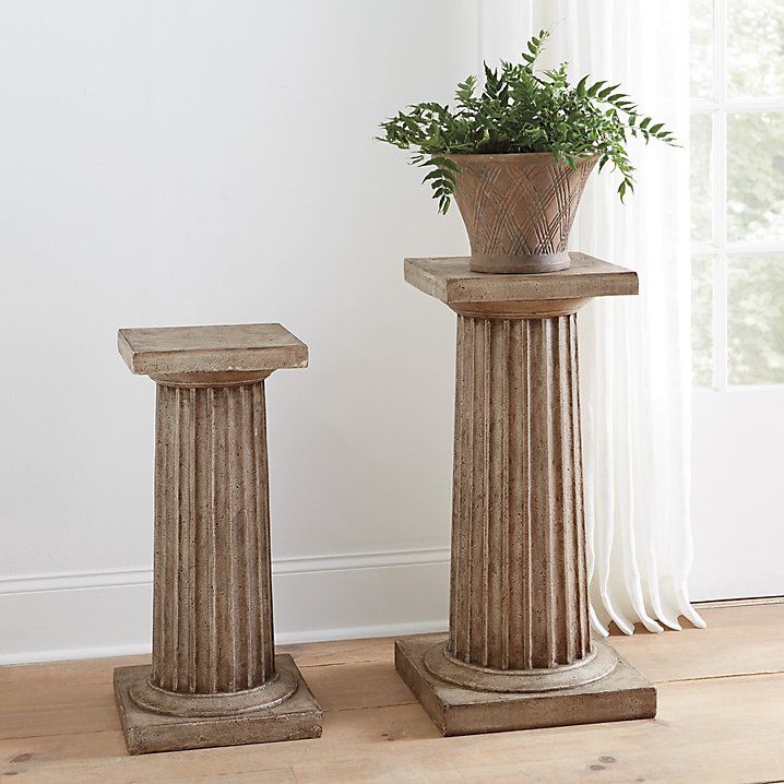 two stone pedestals with a plant in them