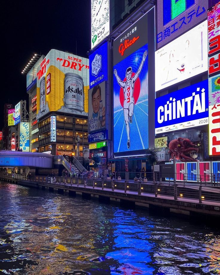 a river running through a city with lots of tall buildings and billboards on it's sides