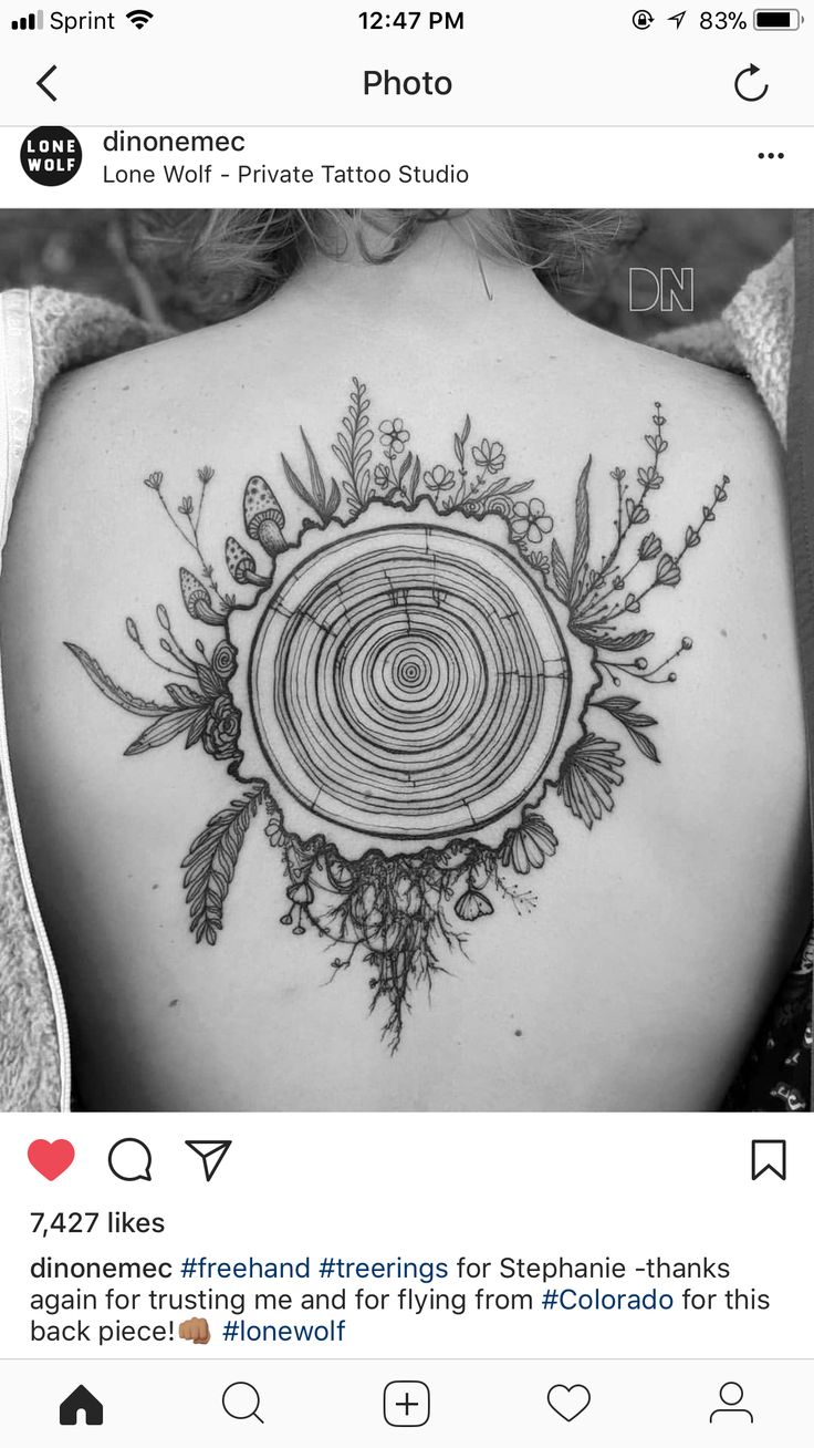 the back of a woman's shoulder with a tree stump and flowers on it