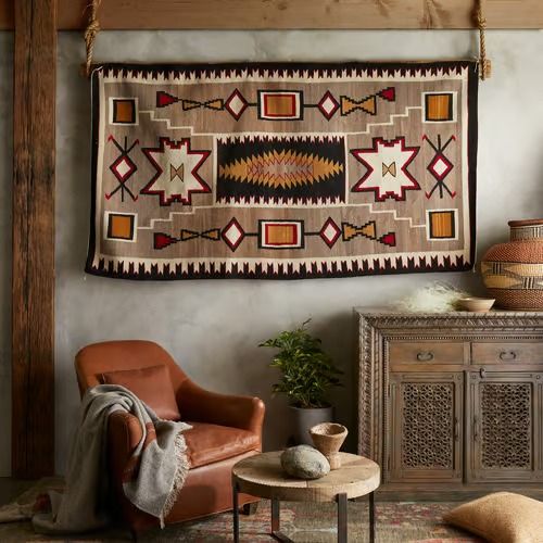 a living room filled with furniture and a large rug hanging on the wall above it