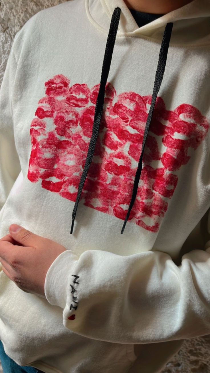 a person wearing a white hoodie with red flowers on the front and black drawstrings