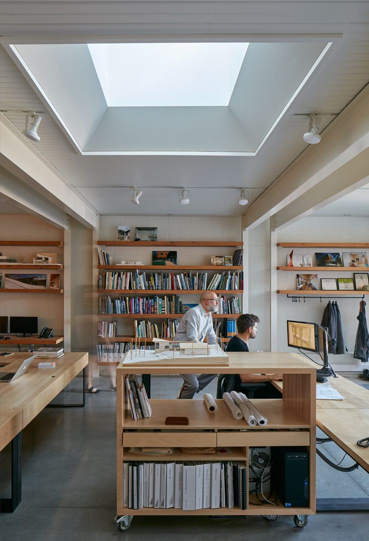 two people sitting at a desk in front of a bookshelf filled with books