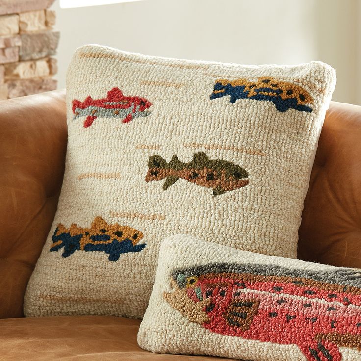 two pillows sitting on top of a brown couch