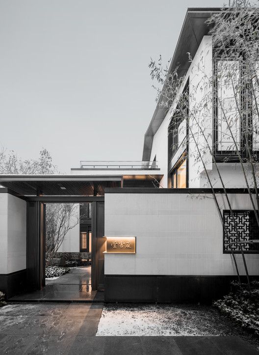 an entrance to a modern house with white walls and black trim on the outside wall