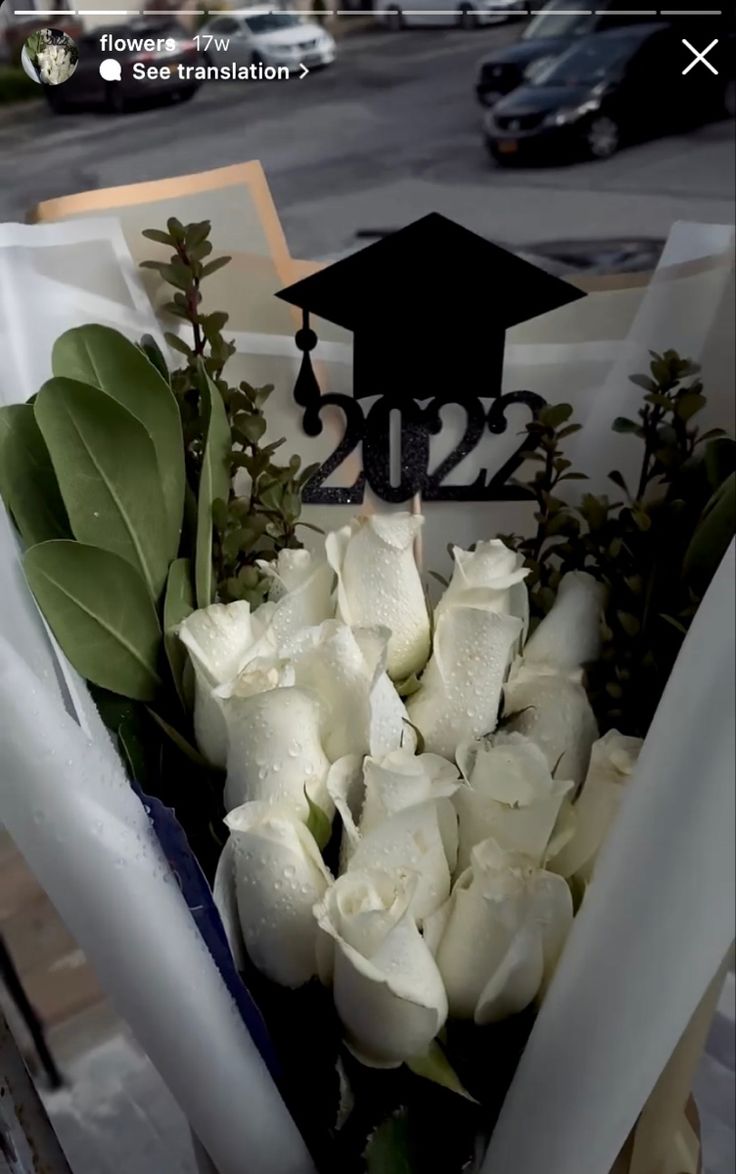 a bouquet of white flowers in front of a graduation cap on top of a sign