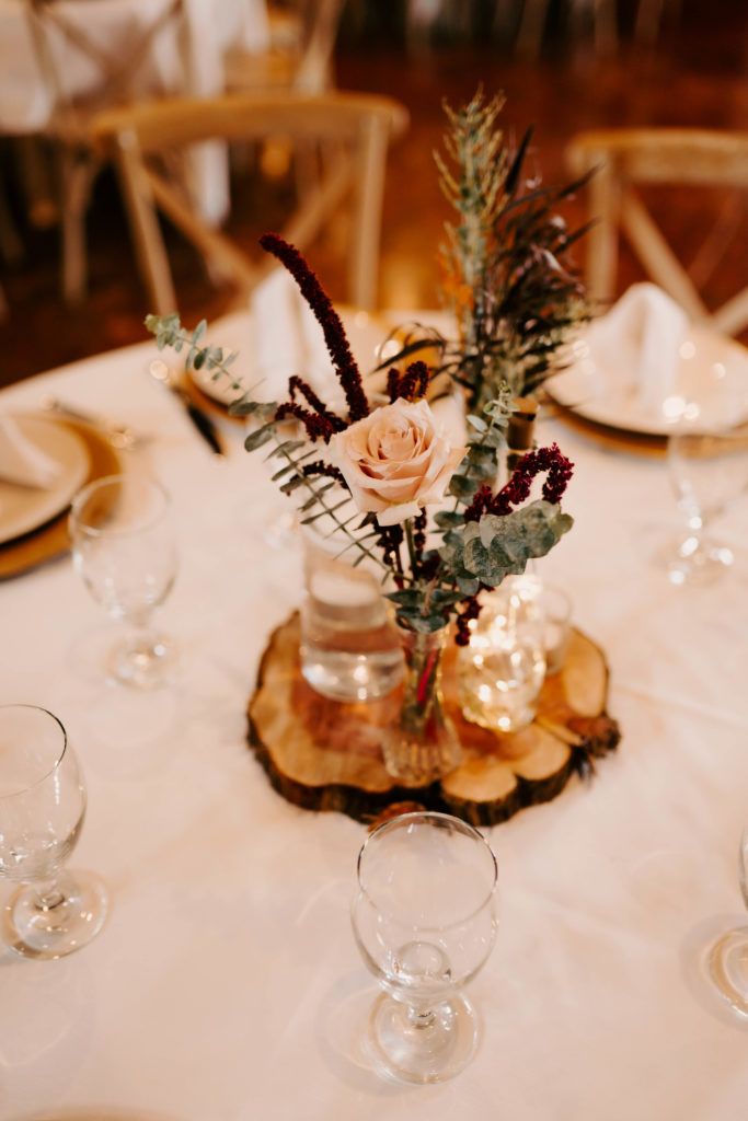 there is a vase with flowers and greenery on it at the center of the table