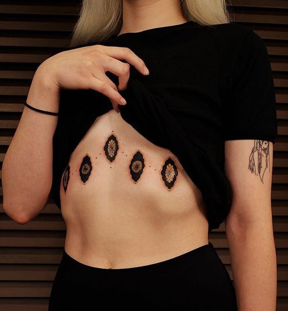 a woman with tattoos on her stomach posing for the camera while wearing a black top