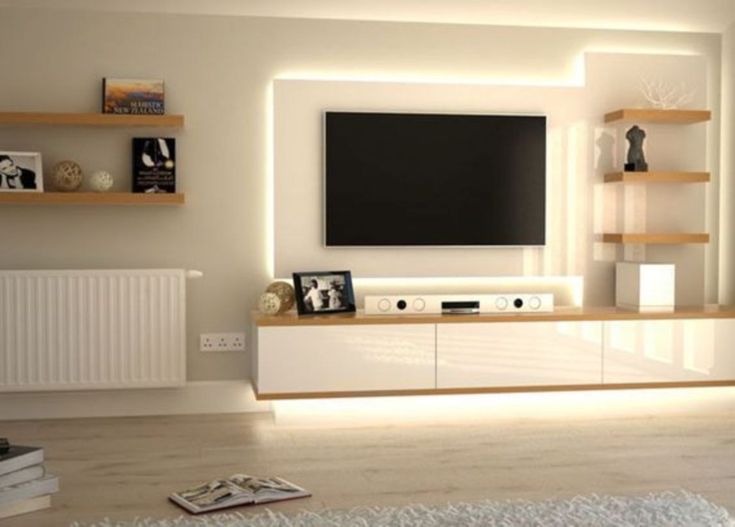 a living room with white furniture and a flat screen tv mounted on the wall above it