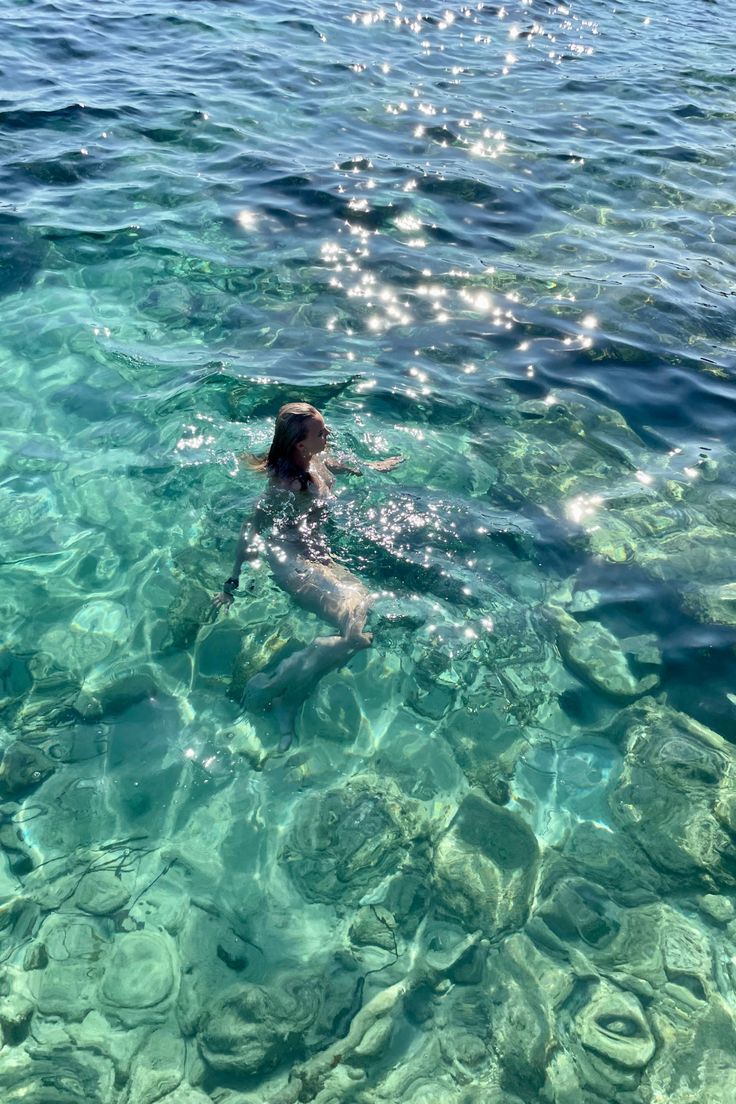 a person swimming in the clear blue water