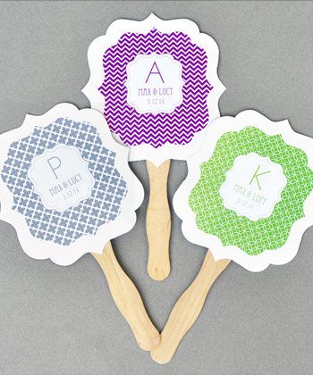 three personalized hand fan shaped like flowers with wooden handles on grey background, one for the monogrammed name and two for the initial