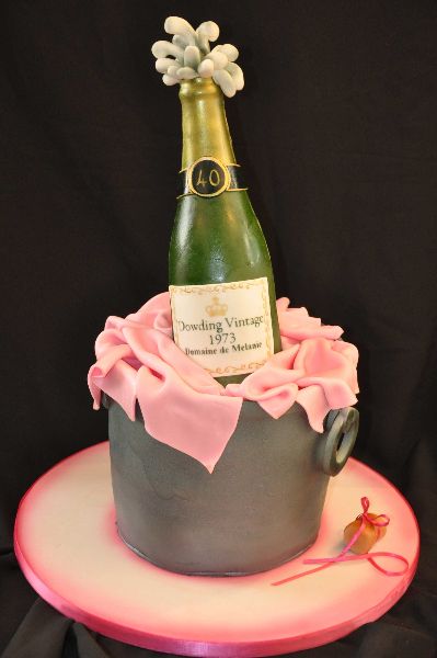 a bottle of champagne sitting on top of a cake with pink frosting around it