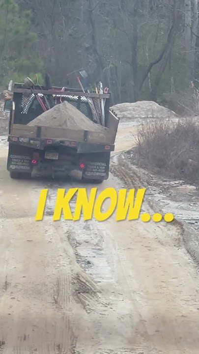 a dump truck driving down a dirt road