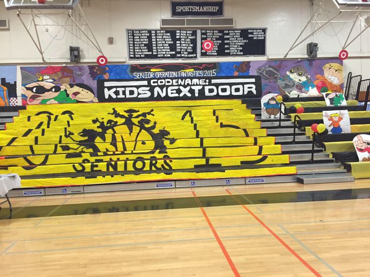 an indoor basketball court decorated with yellow and black banners for the kids next door event