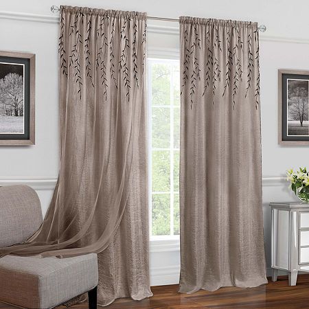 a living room with a chair and window covered in drapes that have vines on them