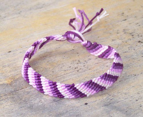 a purple and white striped bracelet on concrete