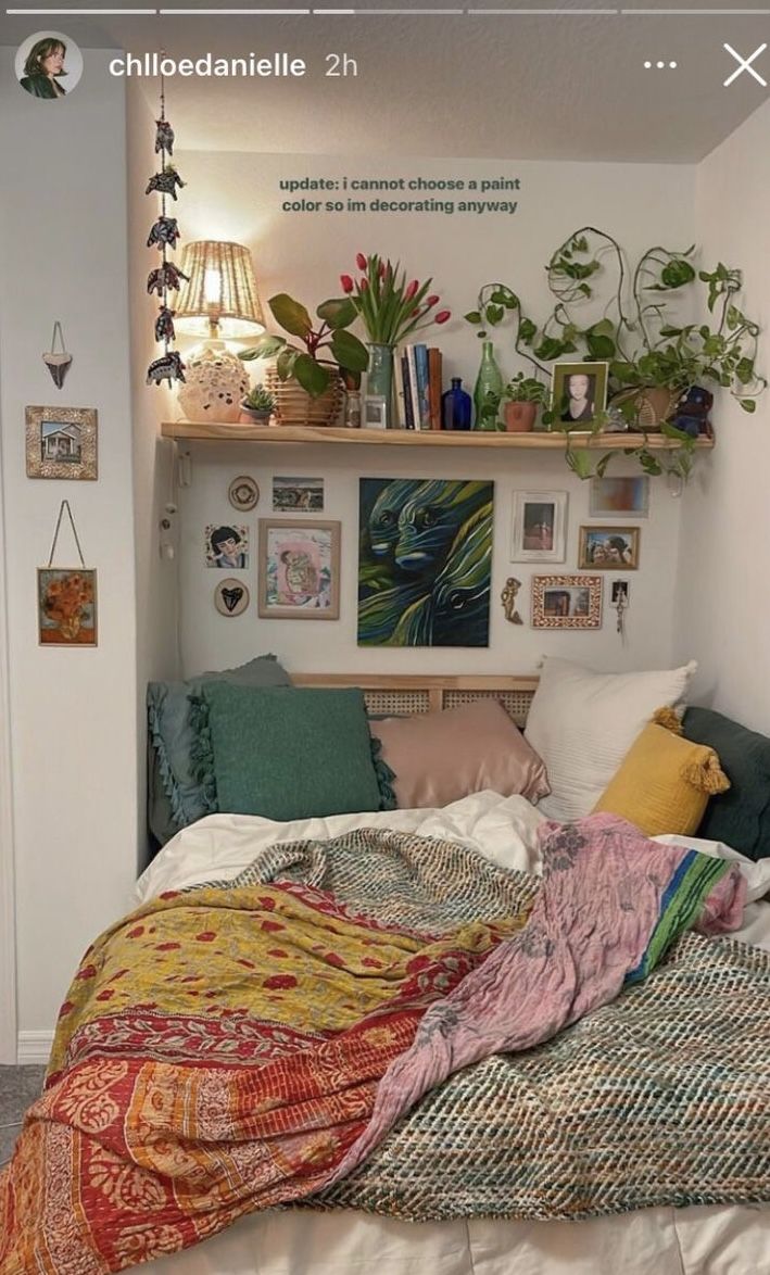 an unmade bed with blankets and pillows in a room filled with potted plants