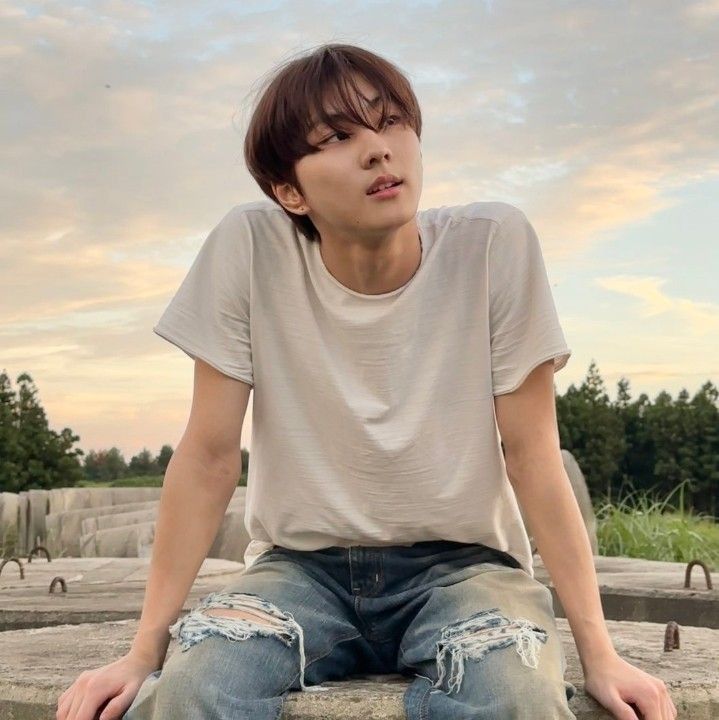 a young man sitting on top of a stone wall