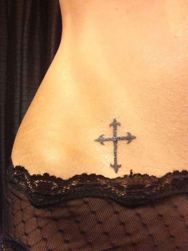 a cross tattoo on the back of a woman's stomach is seen in this image