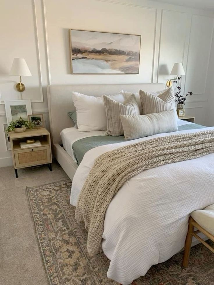 a bed with white sheets and pillows in a bedroom next to a painting on the wall