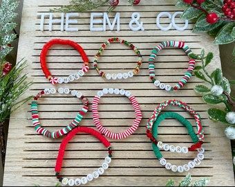 the em & co bracelets are on display in front of holly branches and berries