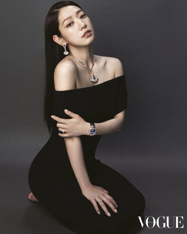 a woman sitting on the ground with her arm around her chest and wearing an off - shoulder black dress