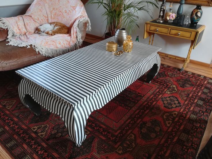 a living room with a striped table cloth on the floor and a dog sleeping on it