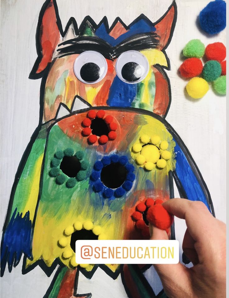 someone is painting an animal with colored pom poms