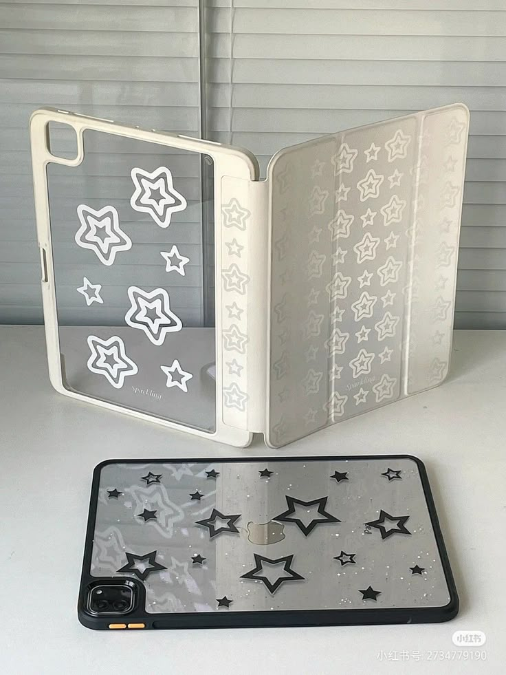 an open book with black and white stars on the cover next to a cell phone