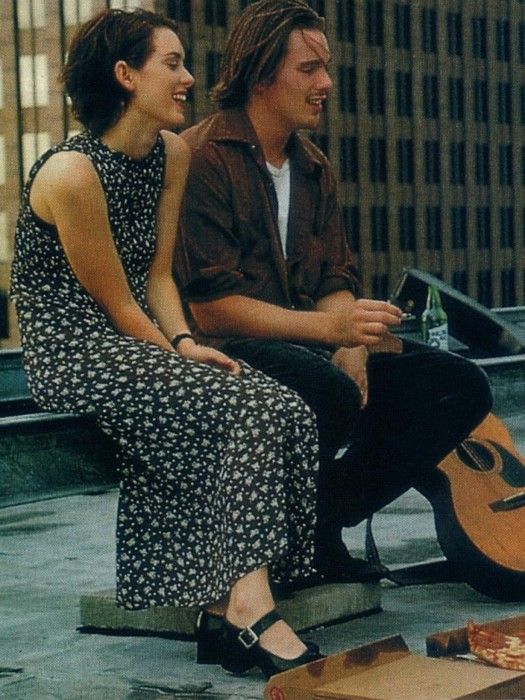 a man and woman sitting on the ground next to a guitar