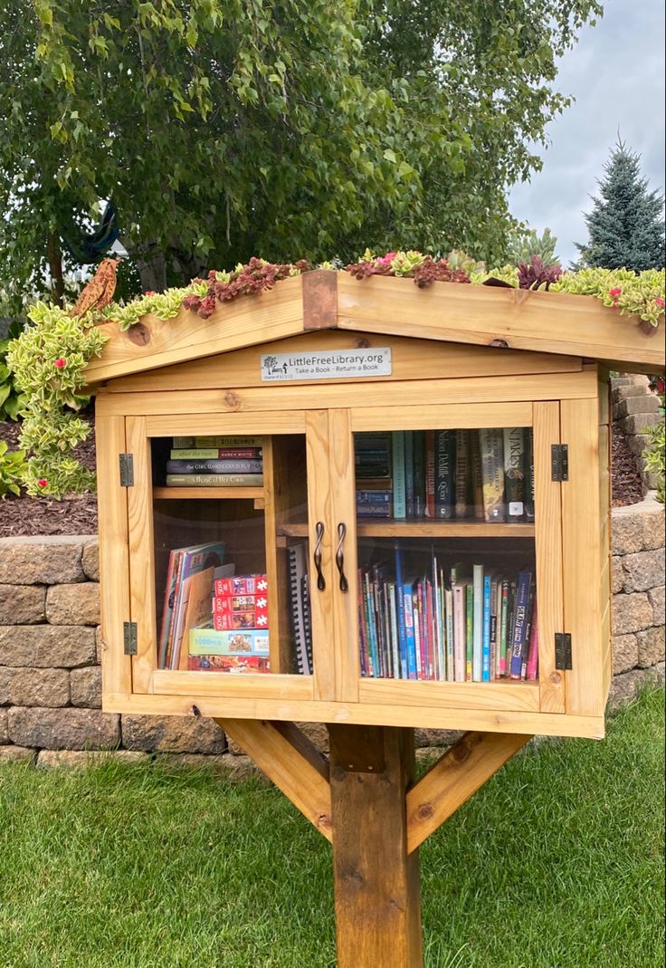 a wooden book stand with books on top of it in the middle of some grass