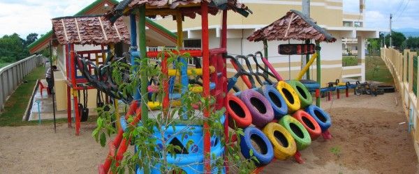 there are many colorful toys in the sand at this play area with umbrellas and trees