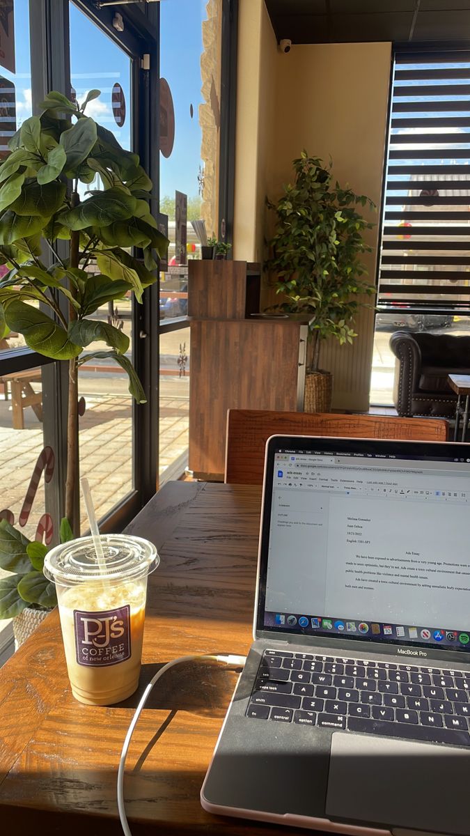 an open laptop computer sitting on top of a wooden table next to a cup of coffee